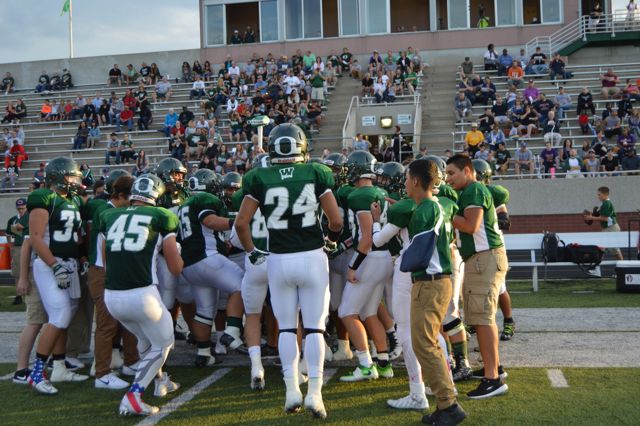 Players huddle around coaches before a game.