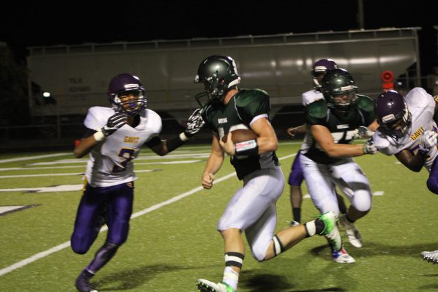 Whiting players in green move through contact with purple-and-white defenders.