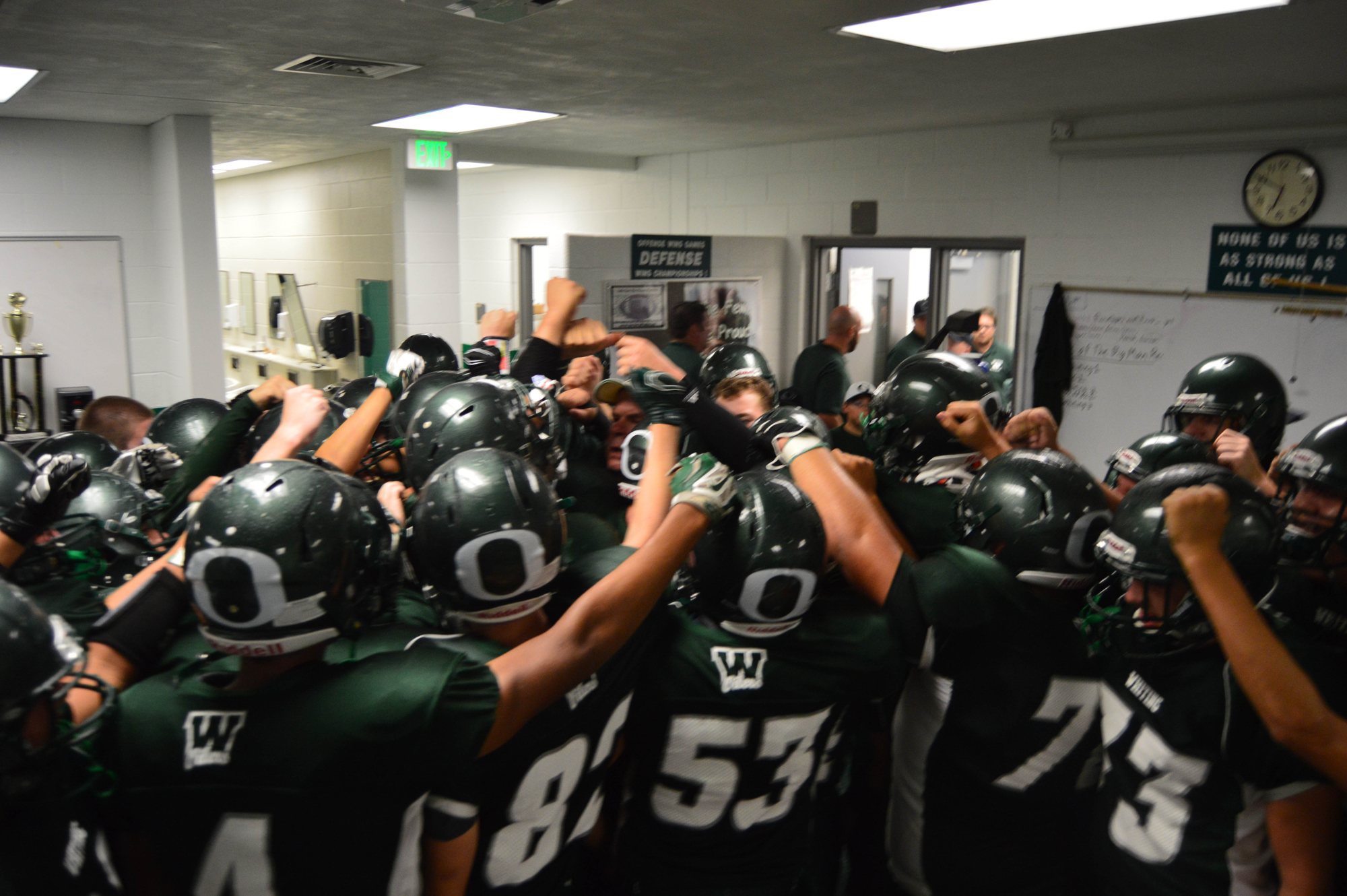 Whiting players bring their hands together in a locker-room huddle.