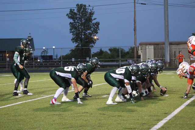 Whiting linemen crouch across from orange-and-green opponents.