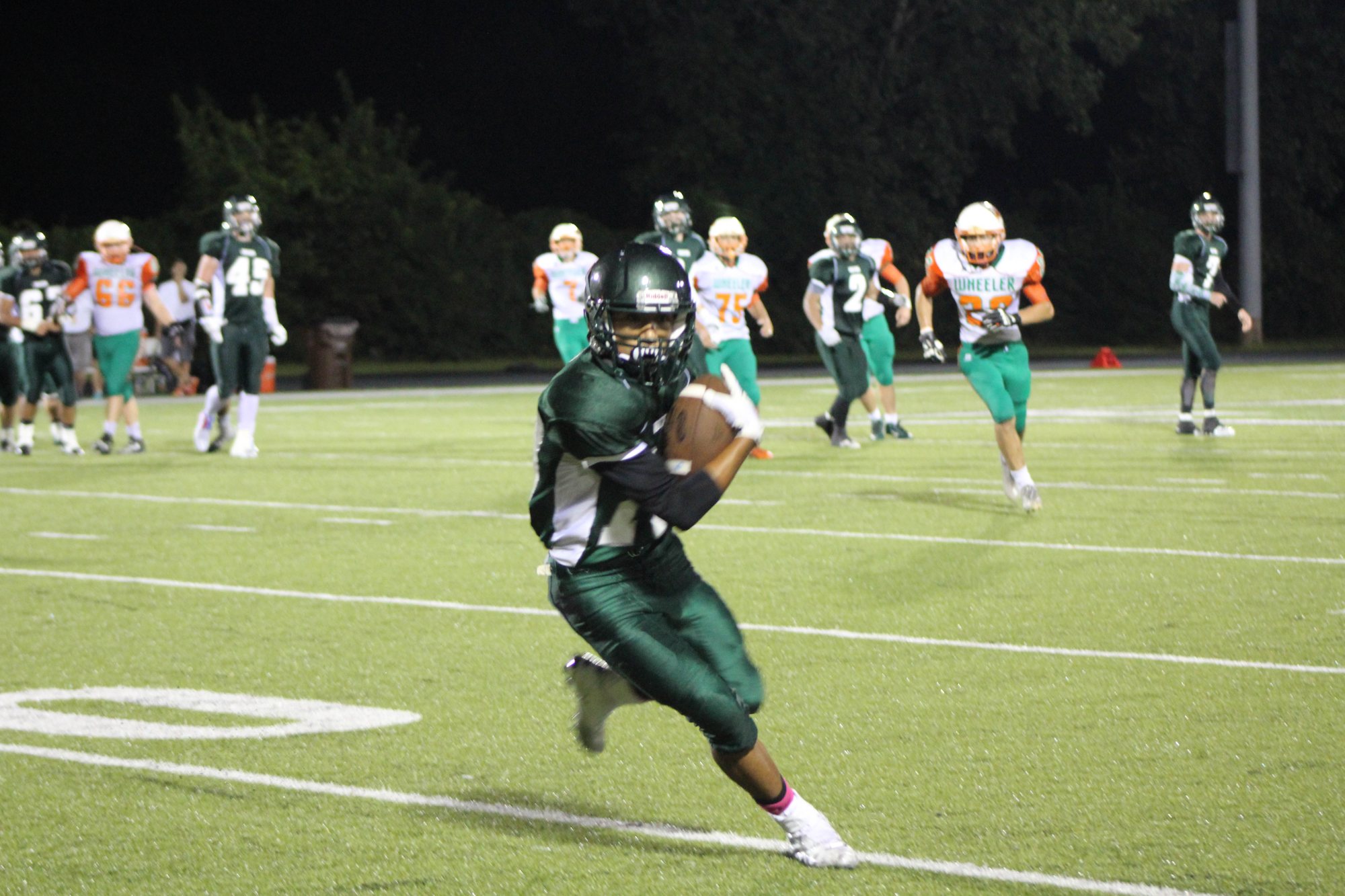 A Whiting ball carrier cuts toward the camera with defenders behind him.