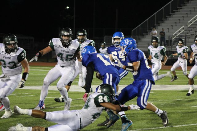 Whiting players in white converge on a runner in blue.