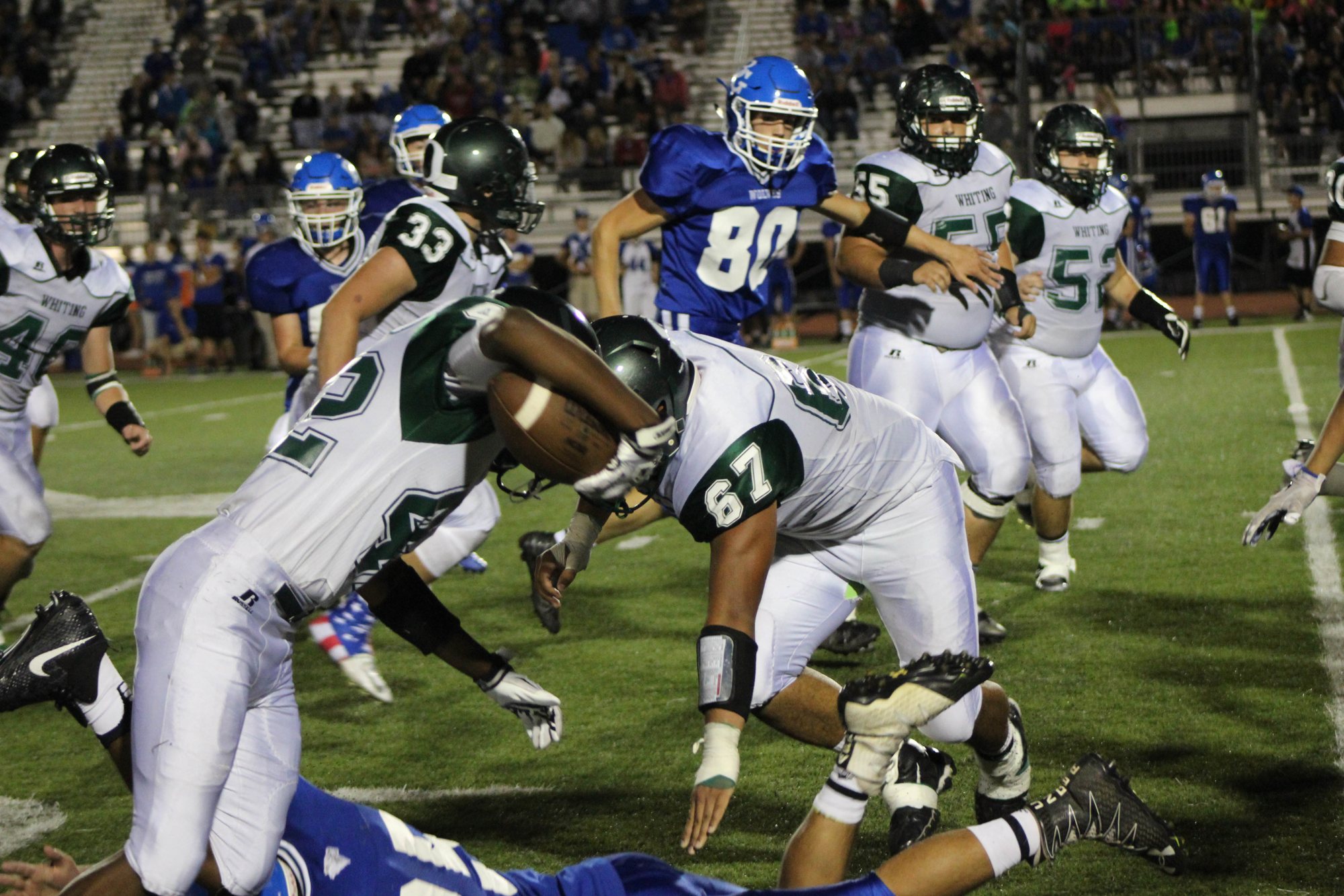 A Whiting ball carrier drives through contact with teammates nearby.