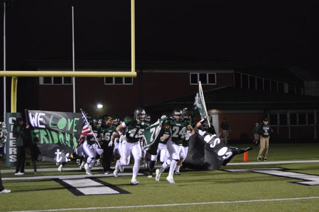 Whiting players run onto the field beneath the goalposts.