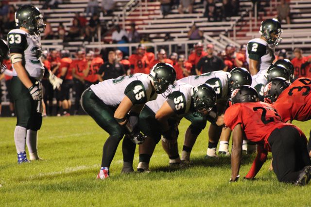 Whiting linemen crouch across from red-and-black opponents.