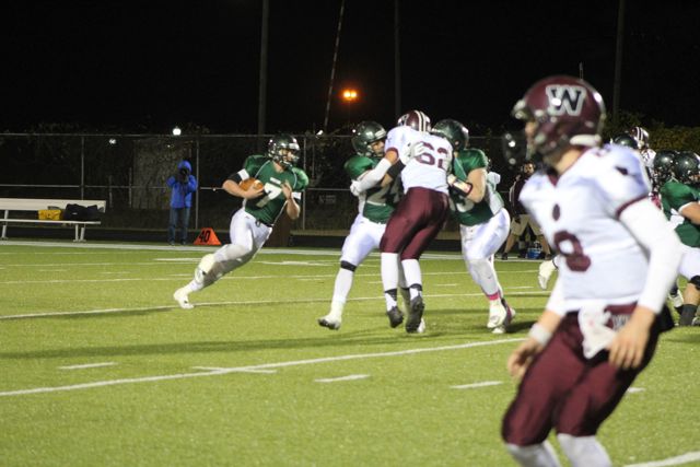 A Whiting quarterback prepares to pass against maroon-and-white opponents.