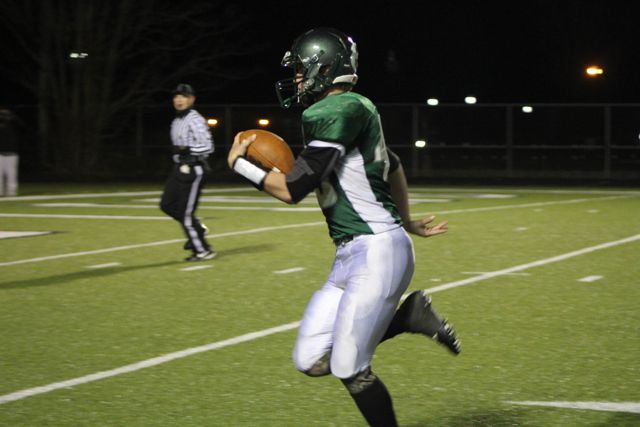 A Whiting ball carrier strides along the sideline under the lights.