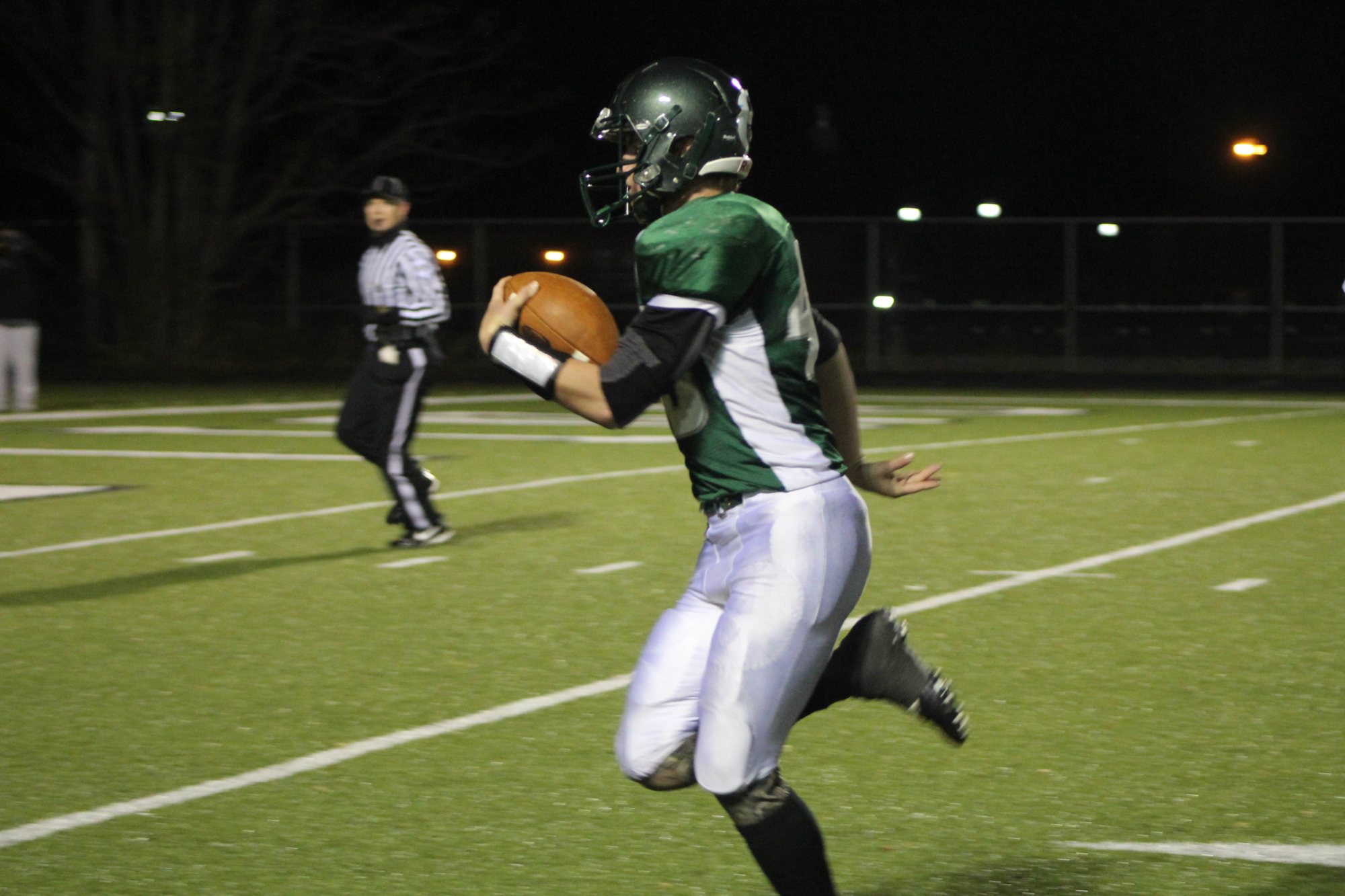 A Whiting ball carrier strides along the sideline under the lights.