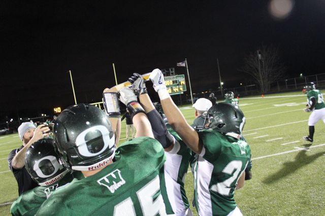 Players raise a trophy together beneath the lights.