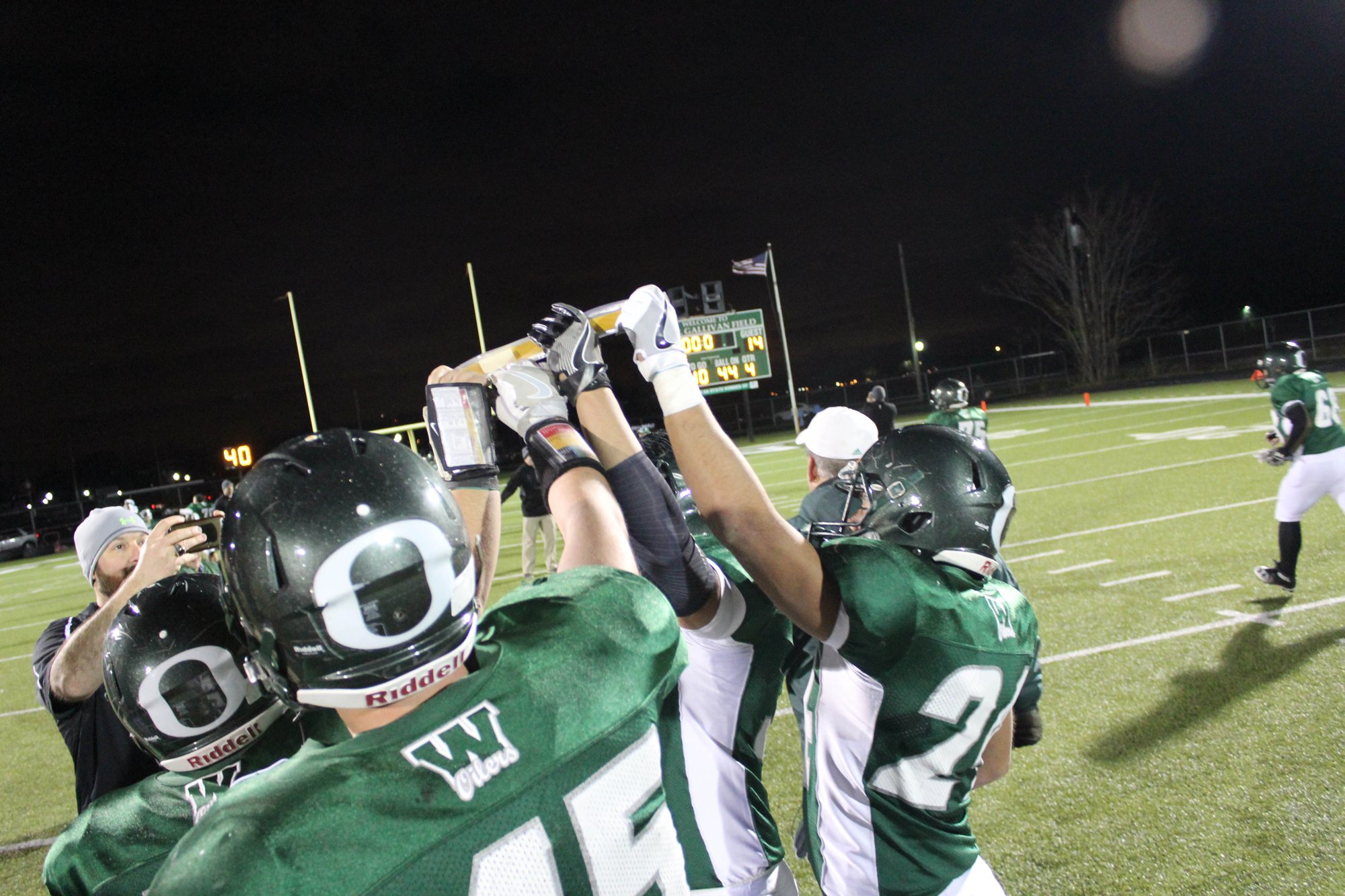 Players raise a trophy together beneath the lights.