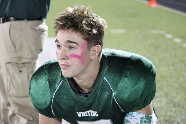 A seated Whiting player listens near the sideline.