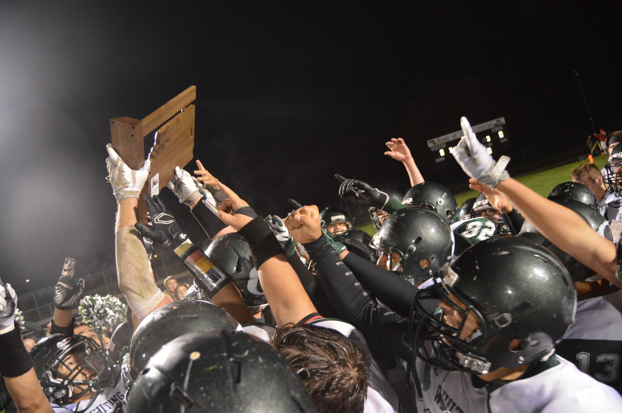 Players in white lift a trophy above their helmets.