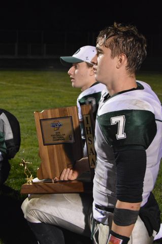A player stands beside a coach holding a trophy.