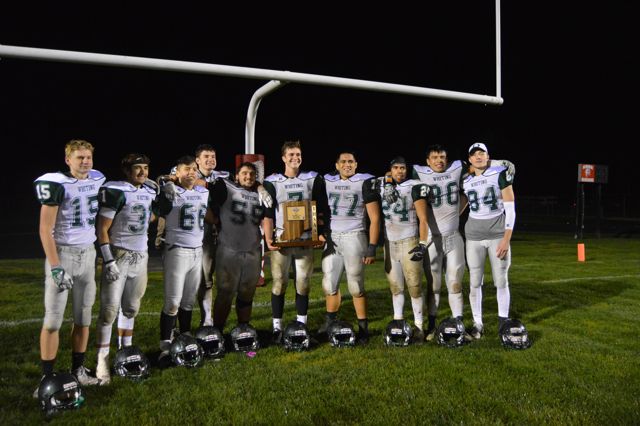 A group of Whiting players pose in a row with a trophy.